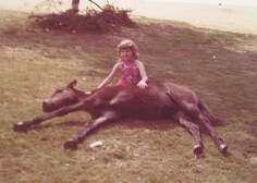 Young Orly Konig sitting next to her horse